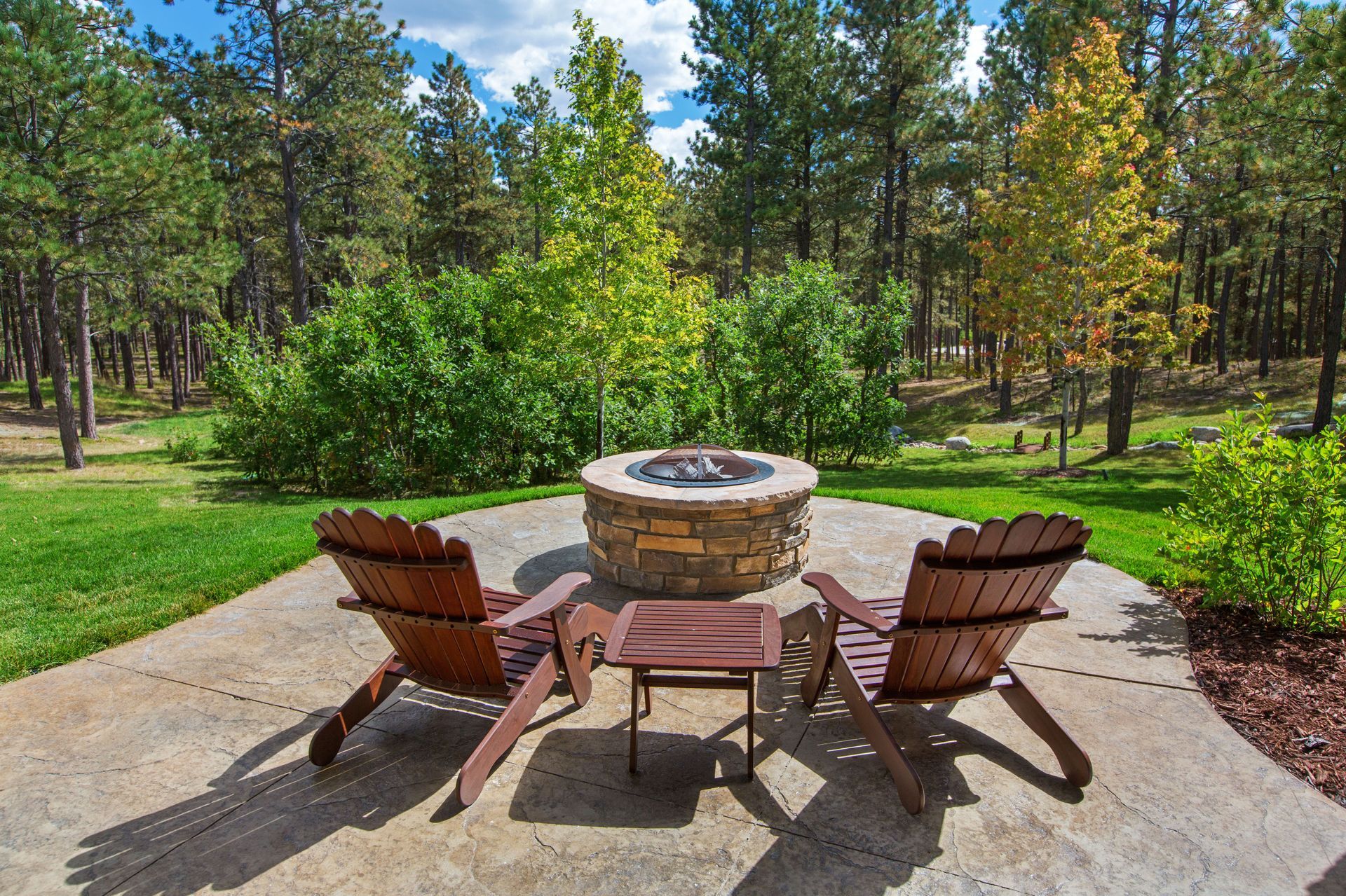 Two wooden chairs are sitting on a patio next to a fire pit.