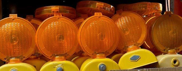 A row of orange traffic lights sitting on top of each other on a shelf.