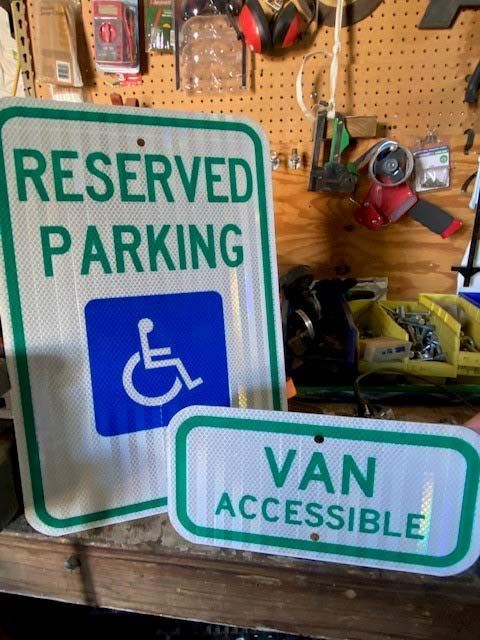 A handicapped parking sign is next to a van accessible sign
