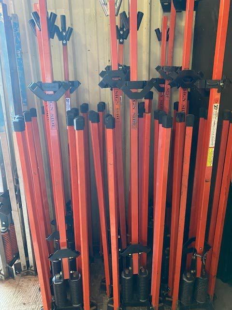 A bunch of orange poles are stacked on top of each other.