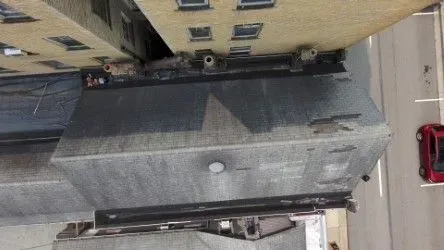 View from above, looking down on a building roof and street with a red car.