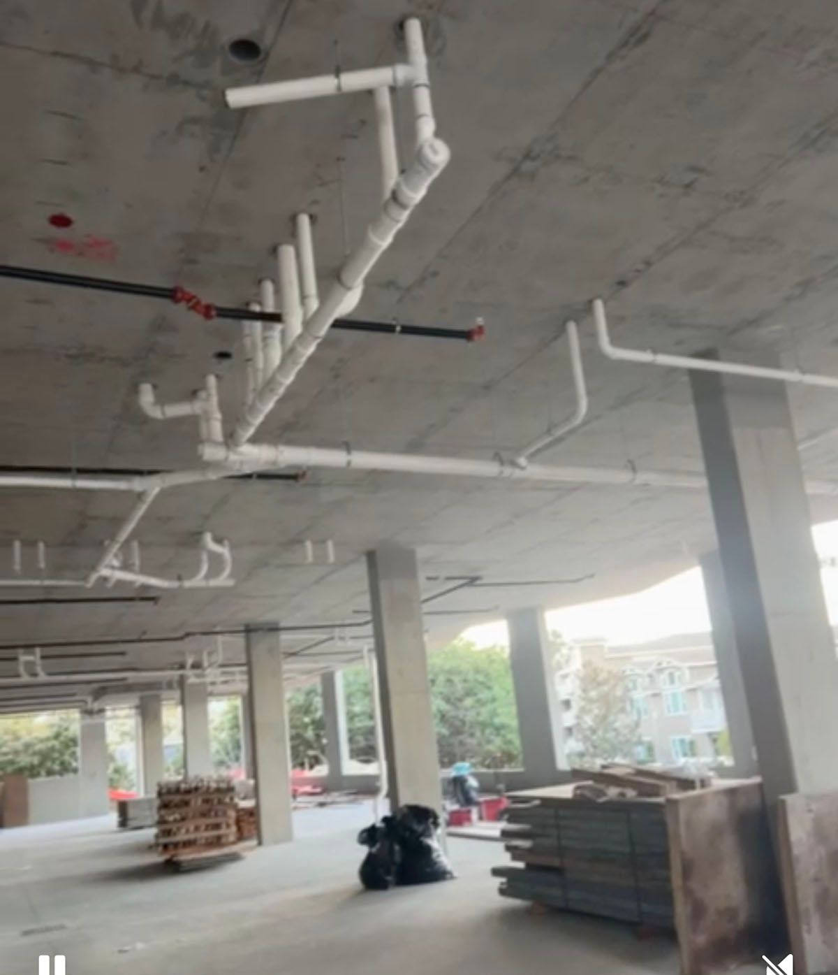 A building under construction with pipes hanging from the ceiling