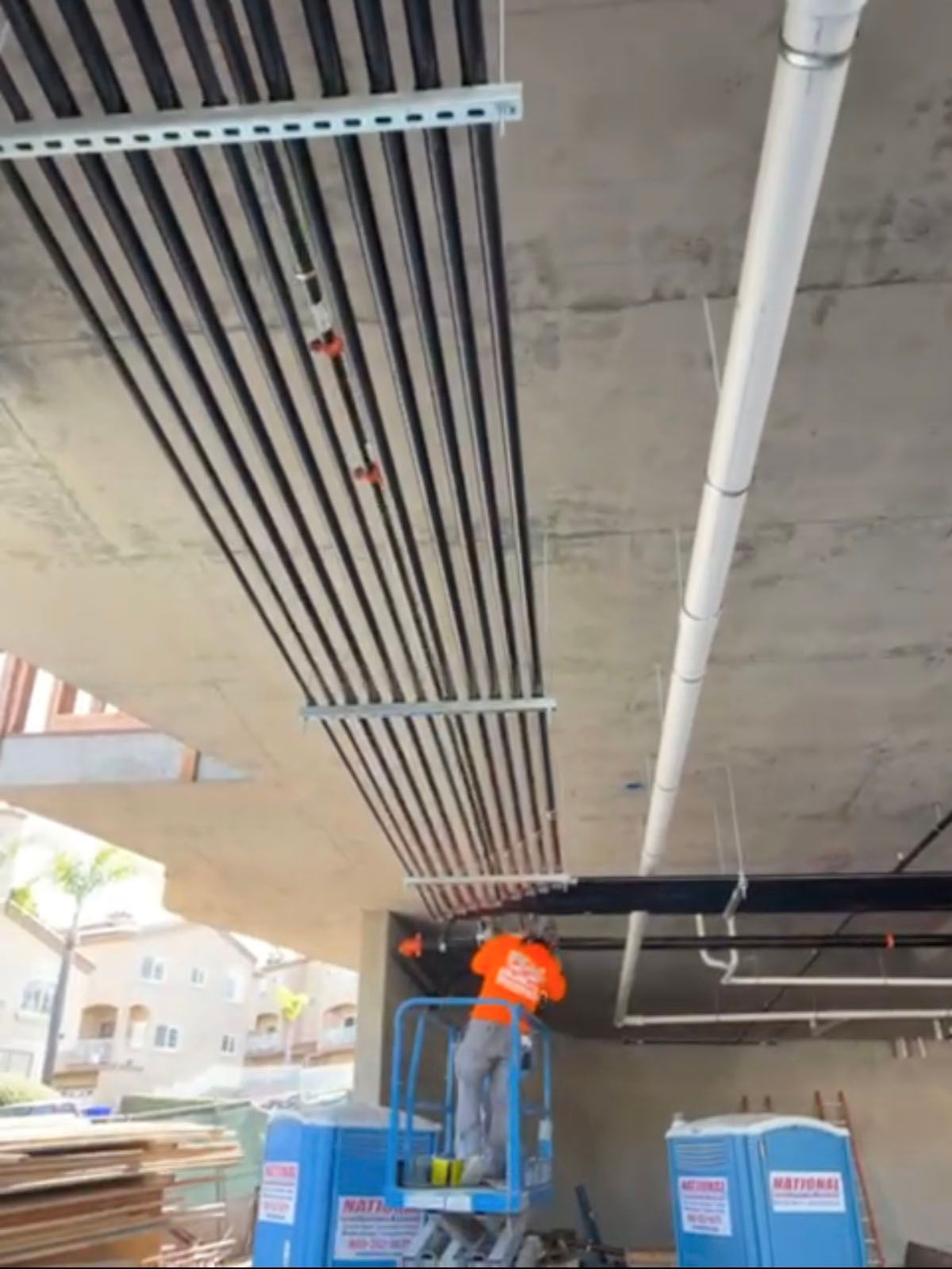 A man is standing on a lift working on pipes