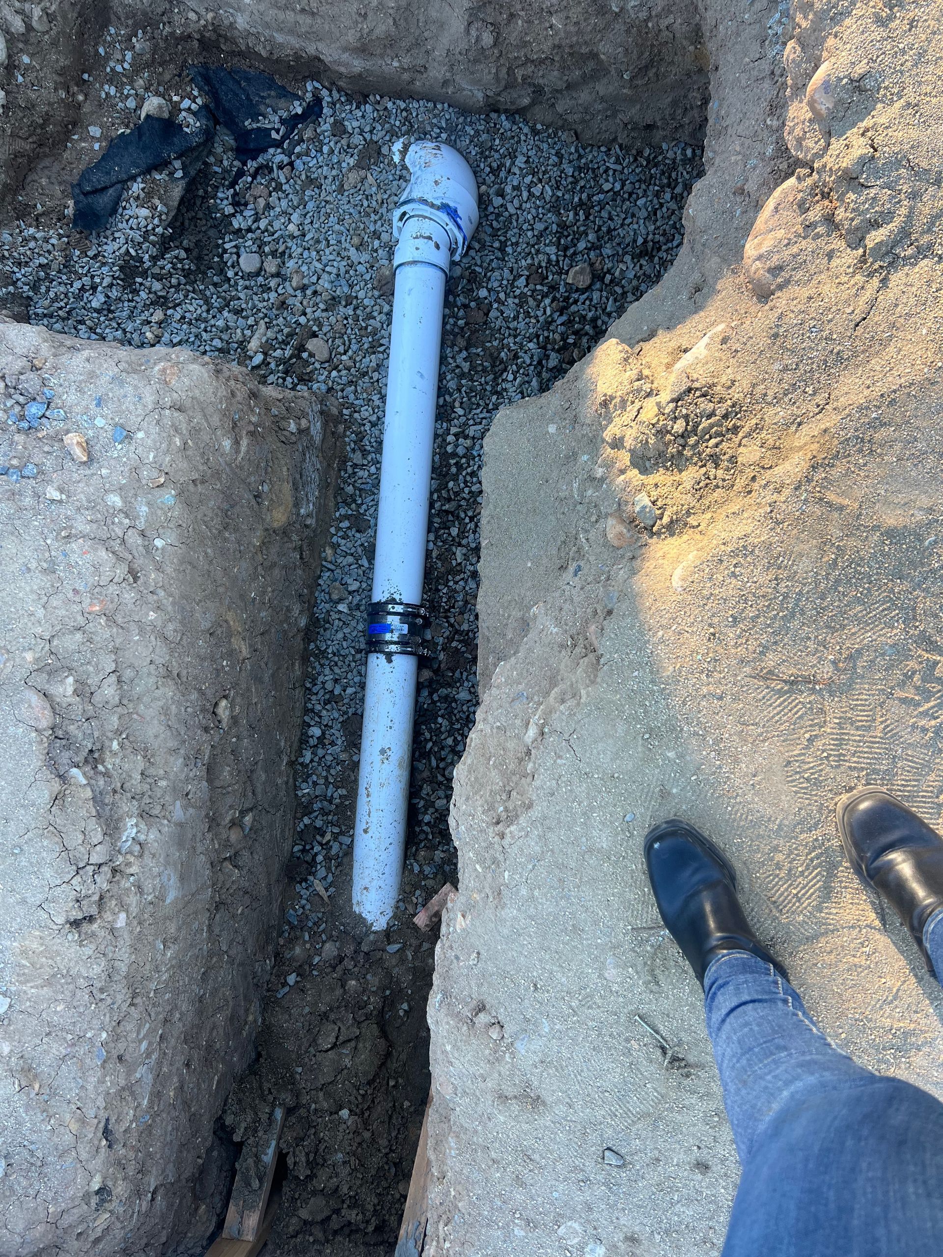 a person is standing next to a white pipe in the dirt