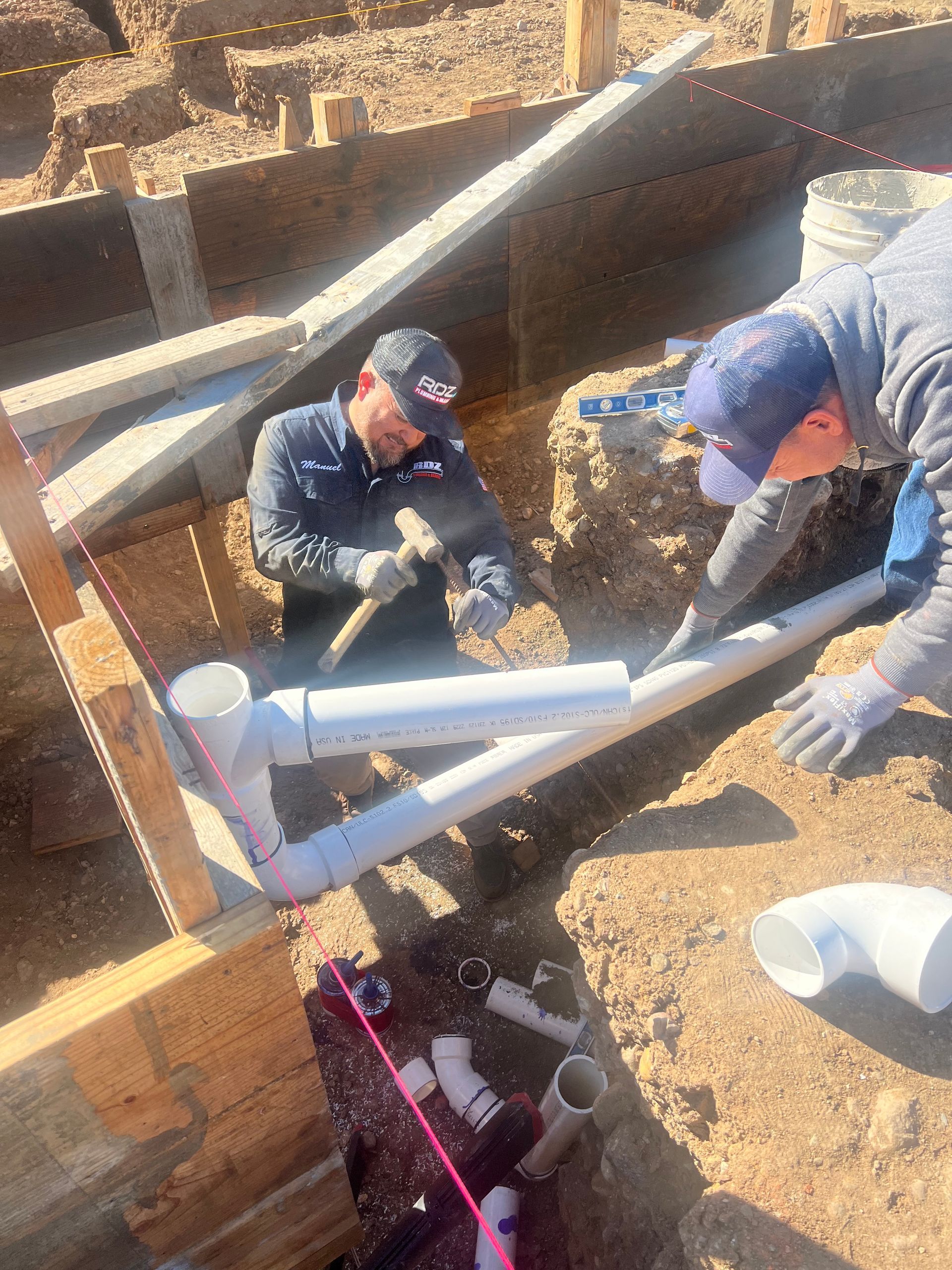 two men are working on a pipe in the dirt