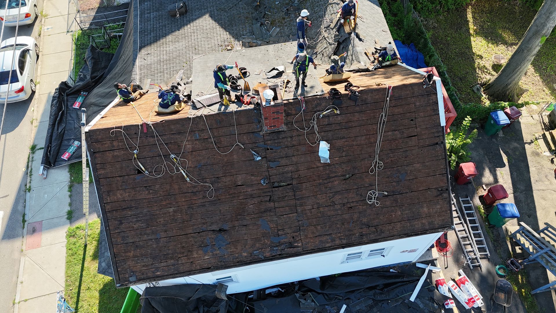 Workers on a house roof during repairs, with tools and materials spread across the shingles