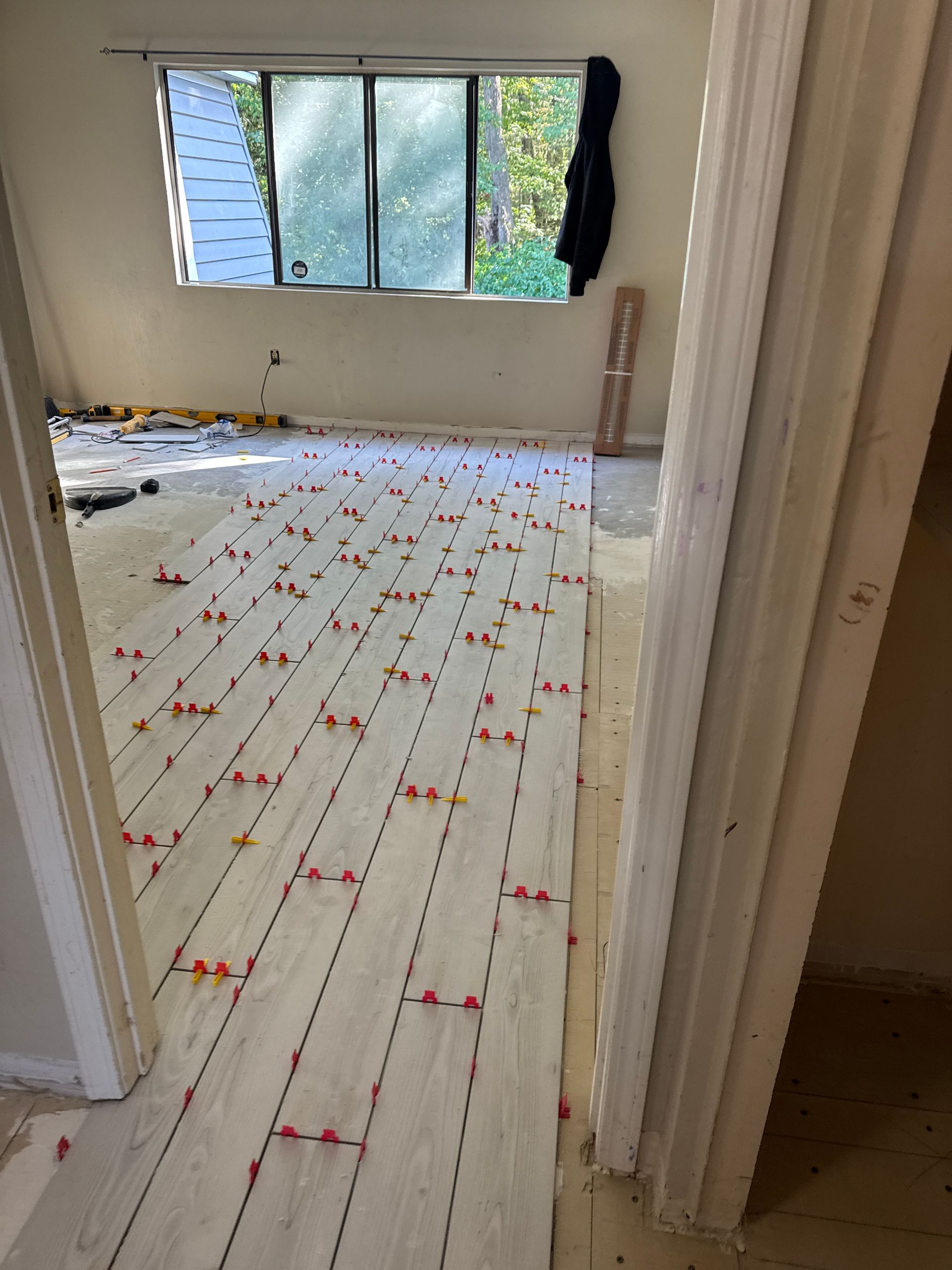 Empty room with white floorboards, open windows, and red confetti scattered across the floor