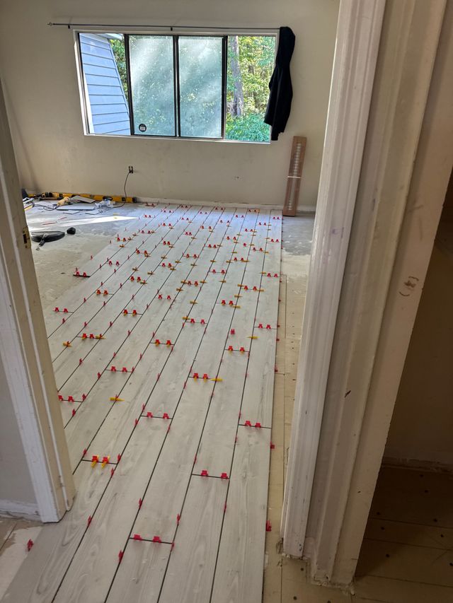 Empty room with white floorboards, red paint streaks, and a window letting in daylight