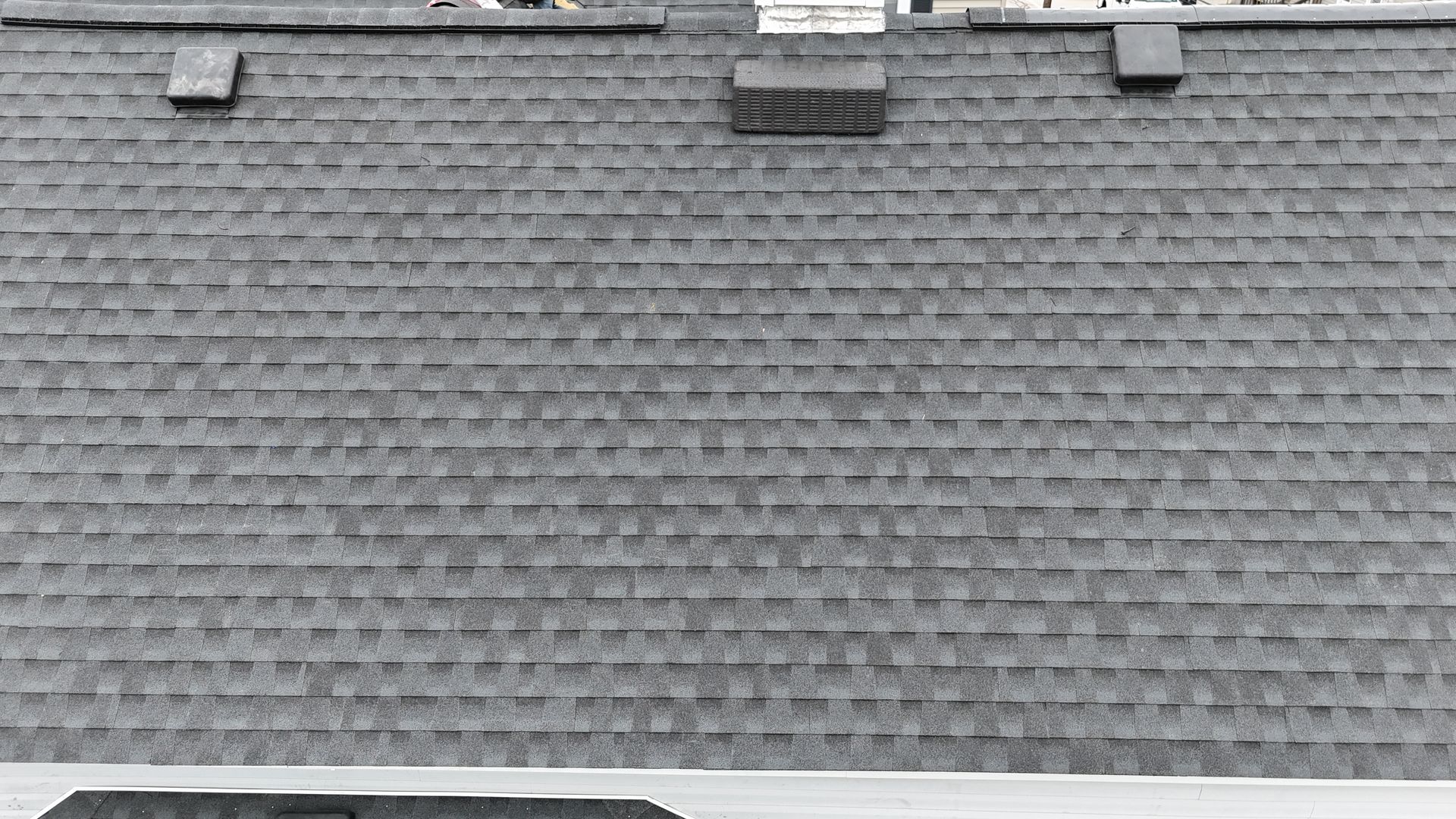 Gray shingled roof with three small roof vents near the top edge