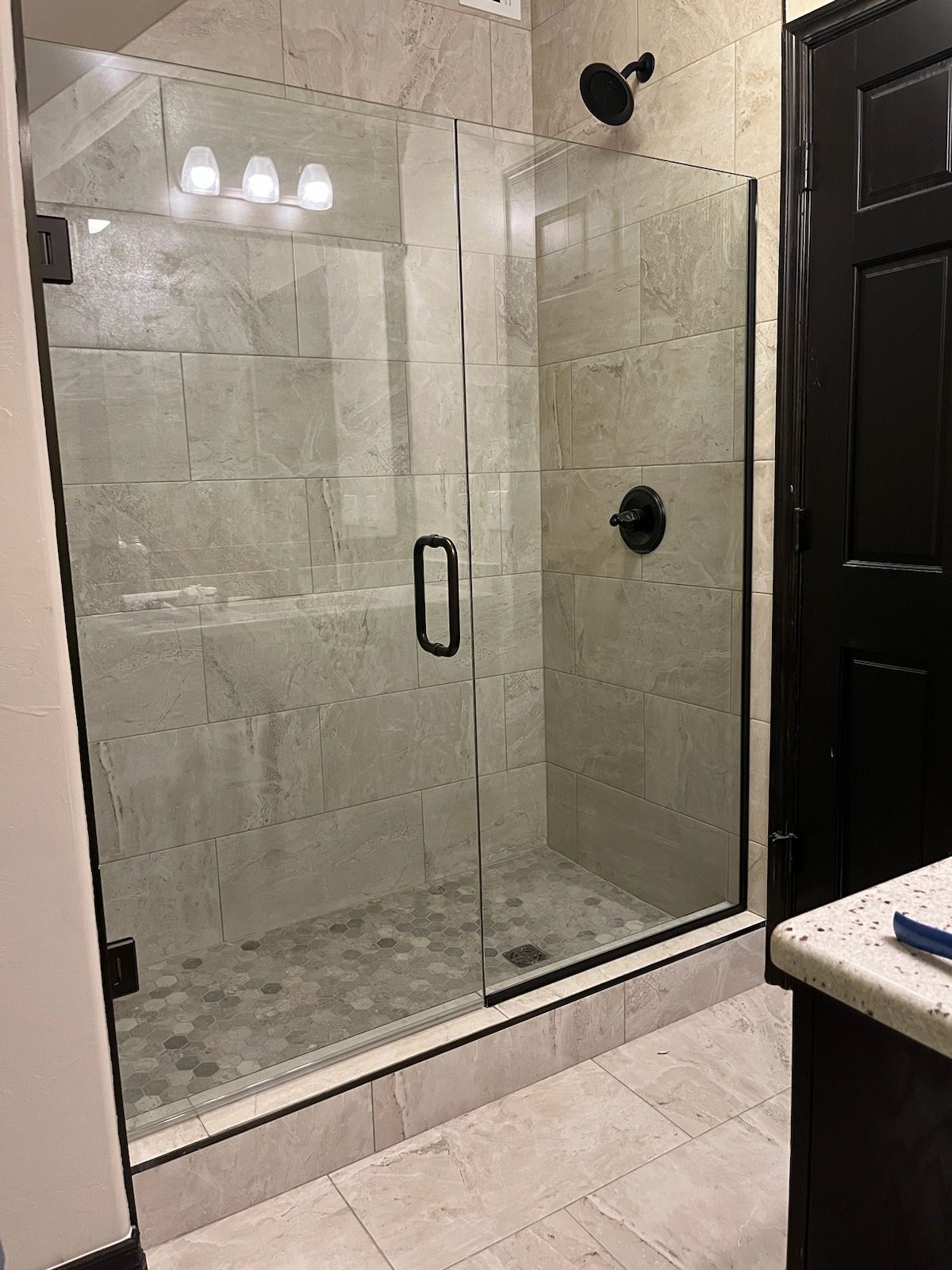 A bathroom with a walk in shower with a glass door.
