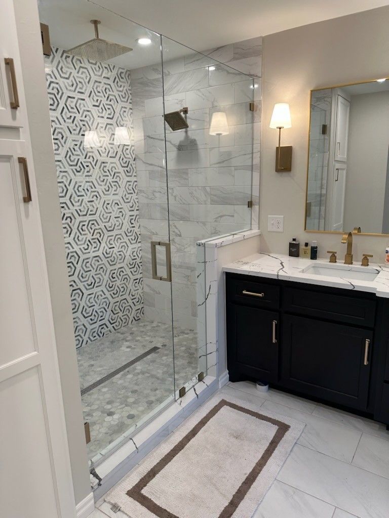 A bathroom with a walk in shower , sink and mirror.