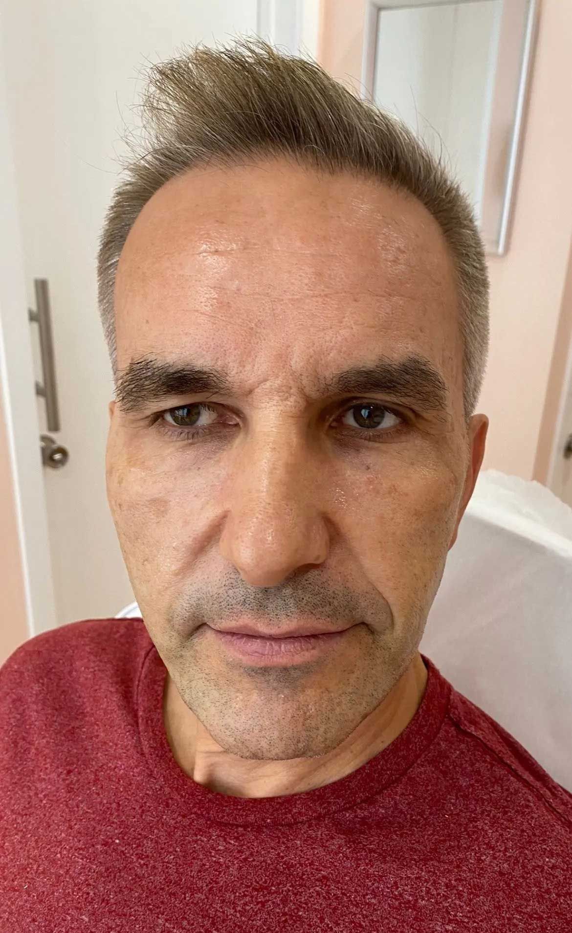 Man with short, light brown hair and red shirt looking at camera.