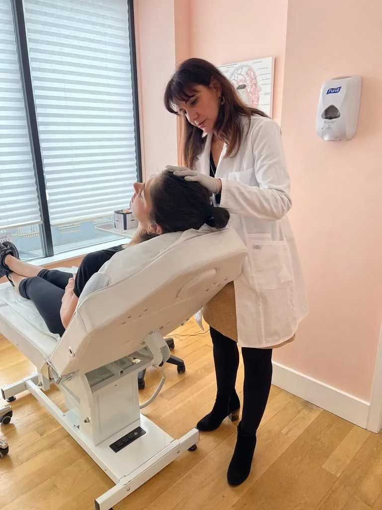 Woman in lab coat examining patient on a medical table in a clinic.