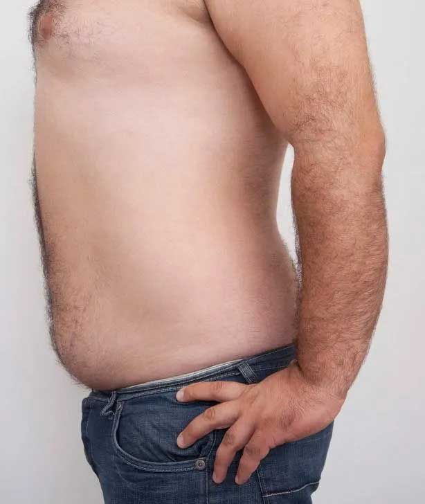 Man with a bare torso and jeans, hand on hip, belly prominent.