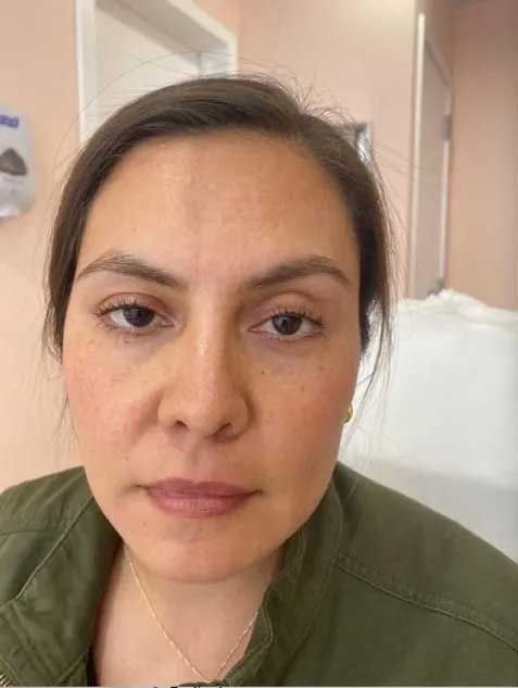 Woman with brown hair and eyes, wearing green jacket, looking at the camera.