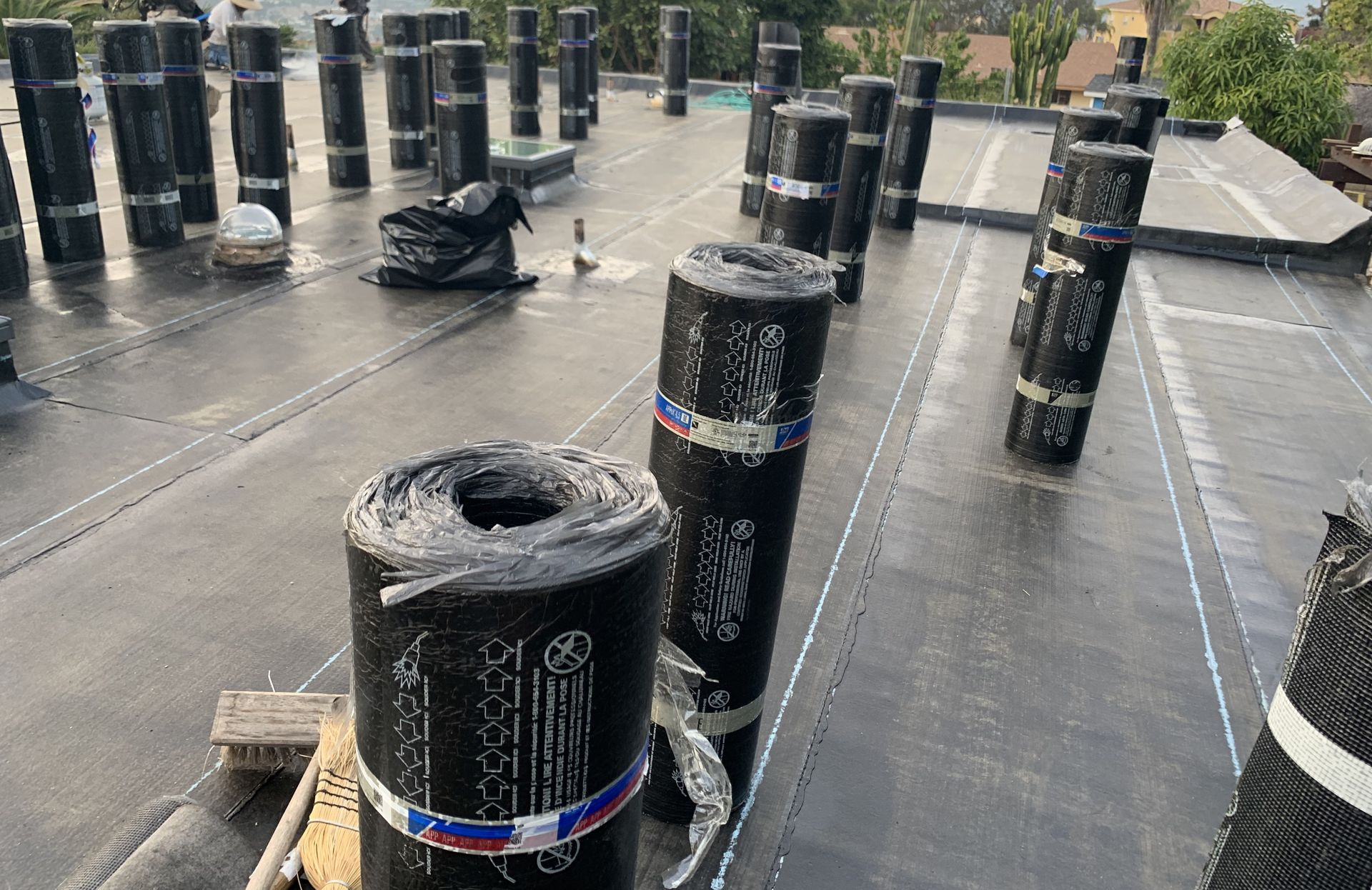 Black rooftop covered with rows of cylindrical vents and piping under construction