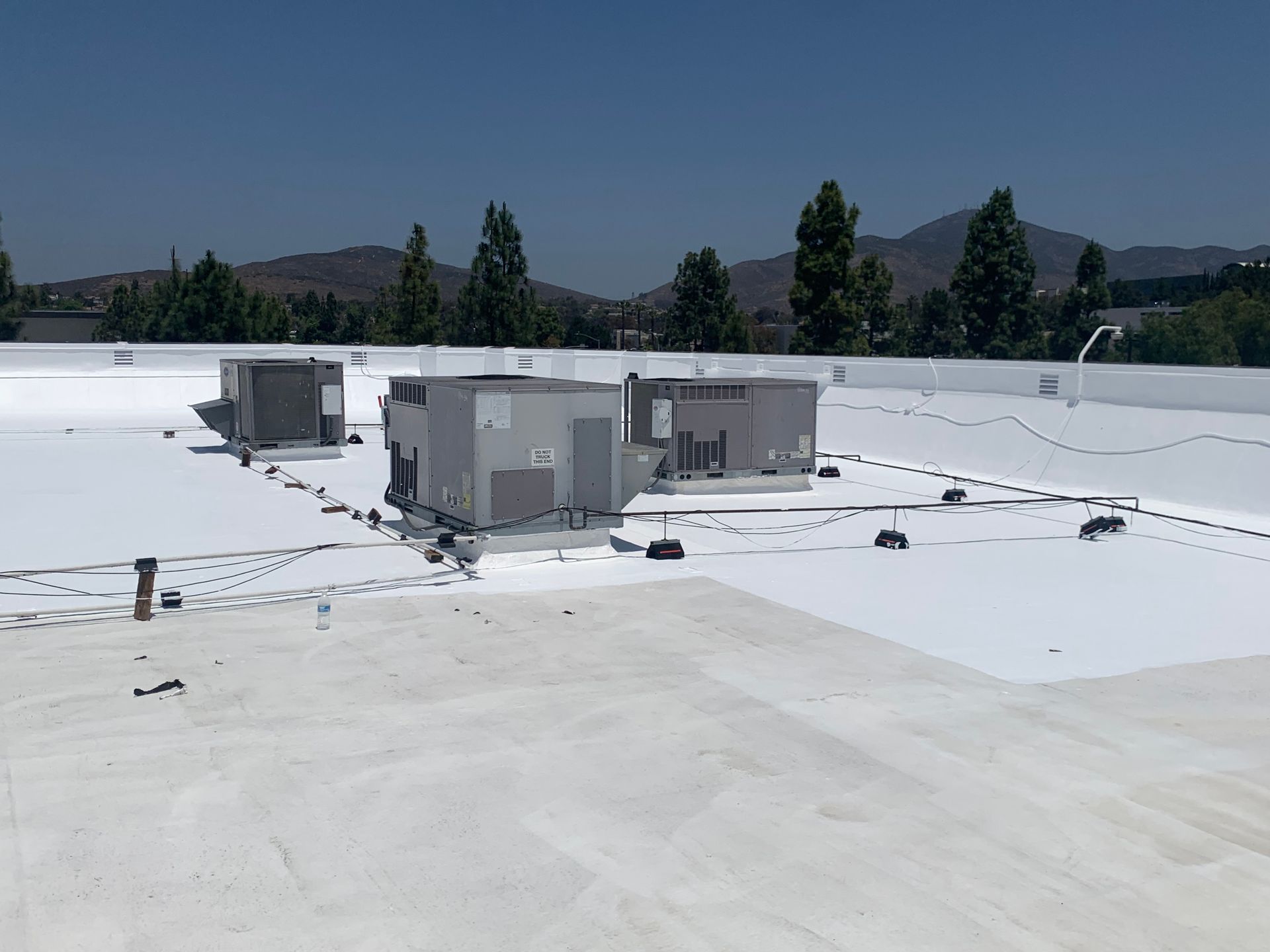 White rooftop with HVAC units and distant mountains under a clear sky