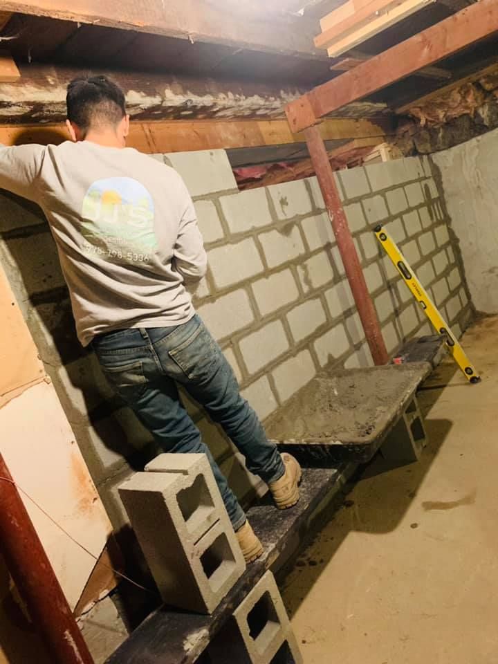 A man is standing on top of a pile of concrete blocks in a basement.