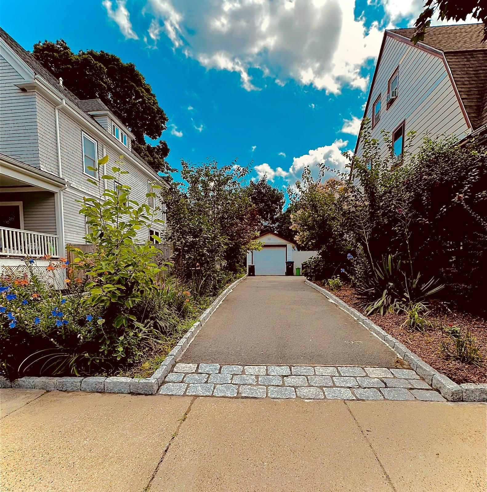 A driveway leading to a white house with a garage
