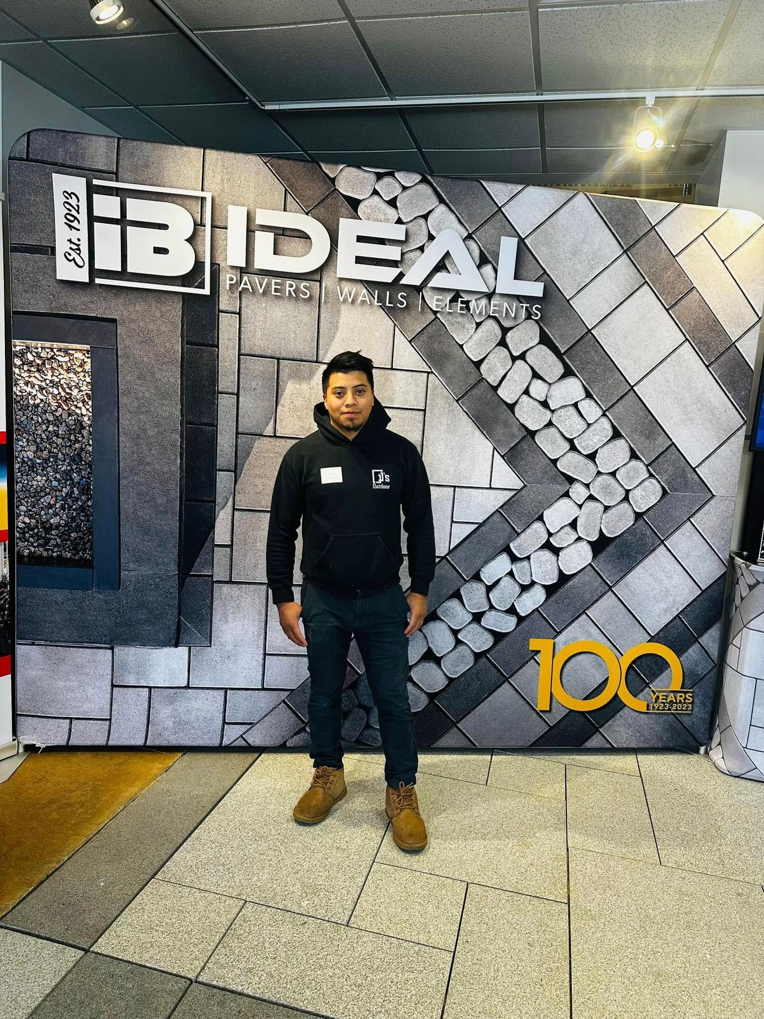 A man is standing in front of a brick wall in a room.