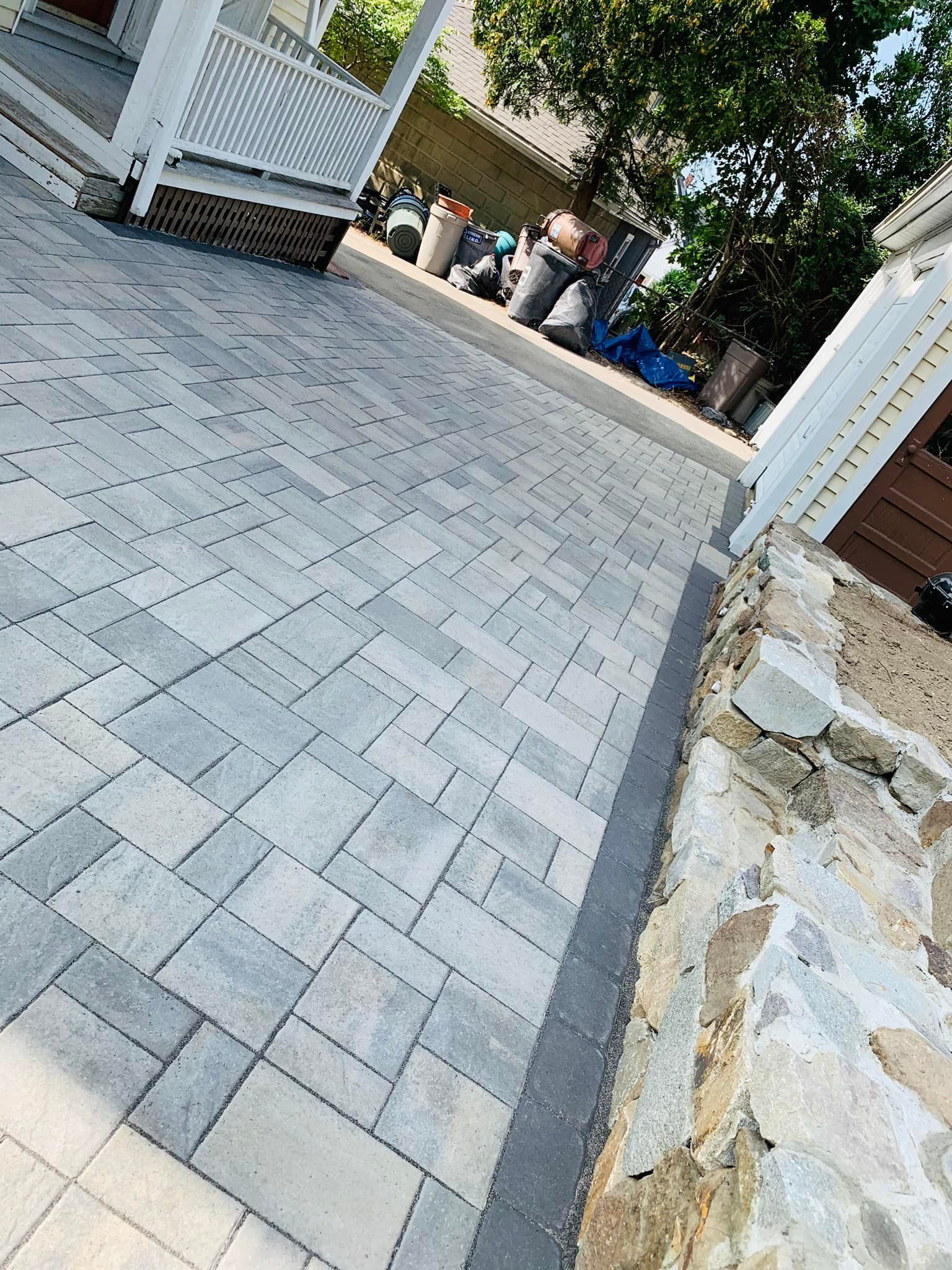 A brick driveway with a stone wall in the background.