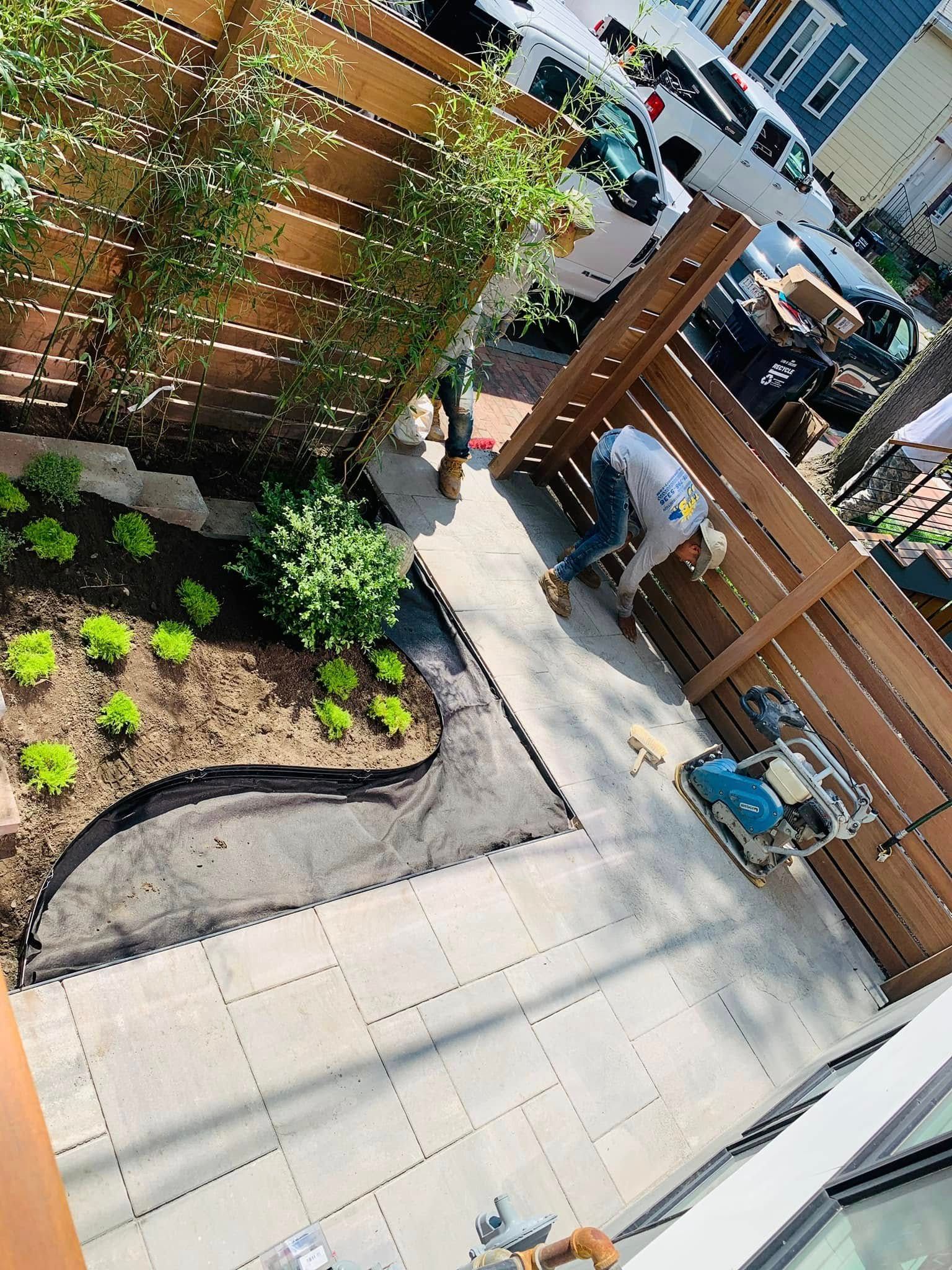 A man is working on a patio in a backyard.