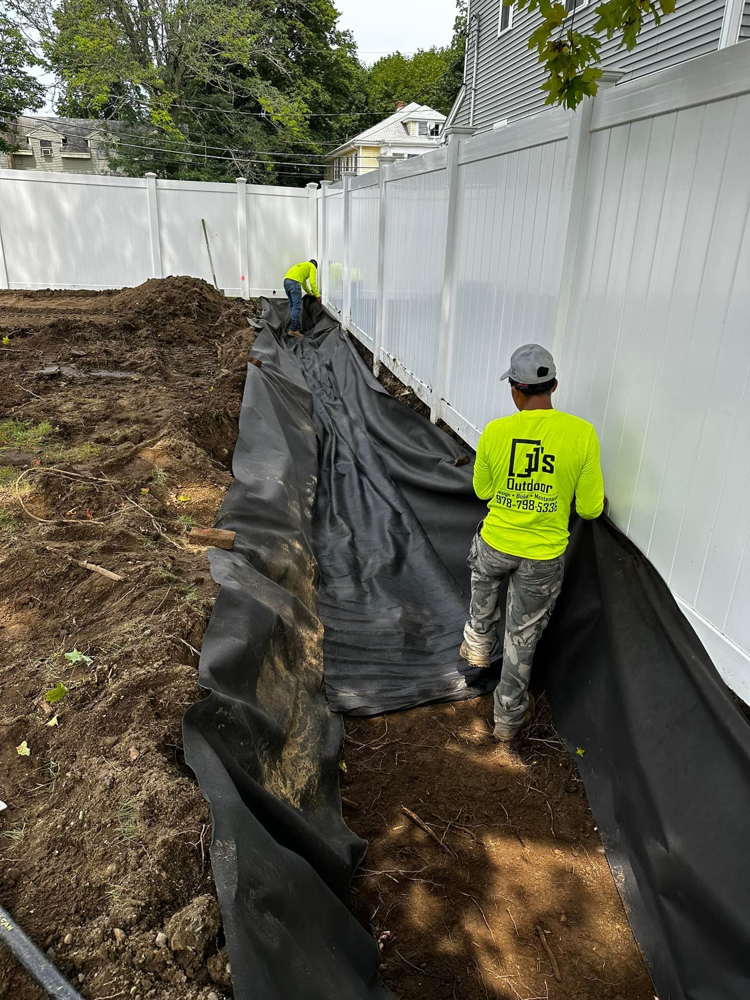A man in a yellow shirt is standing next to a white fence.