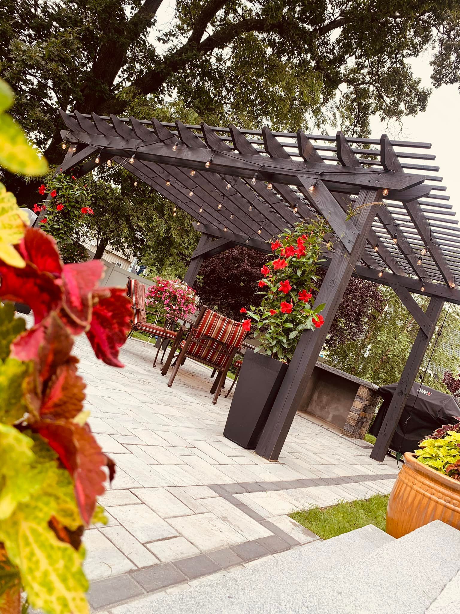A pergola with flowers and chairs in a garden.