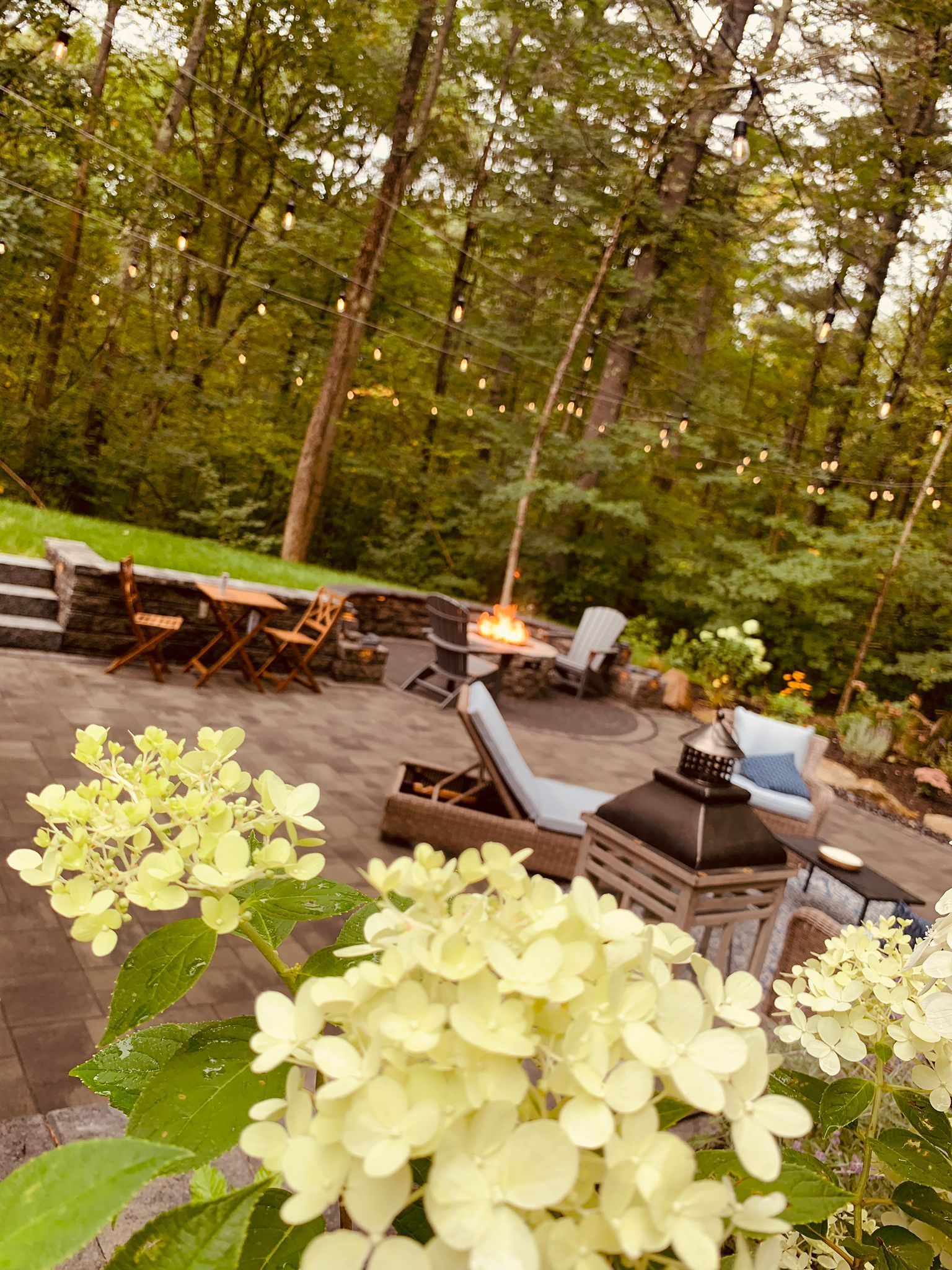 A patio with a fire pit and flowers in the foreground.