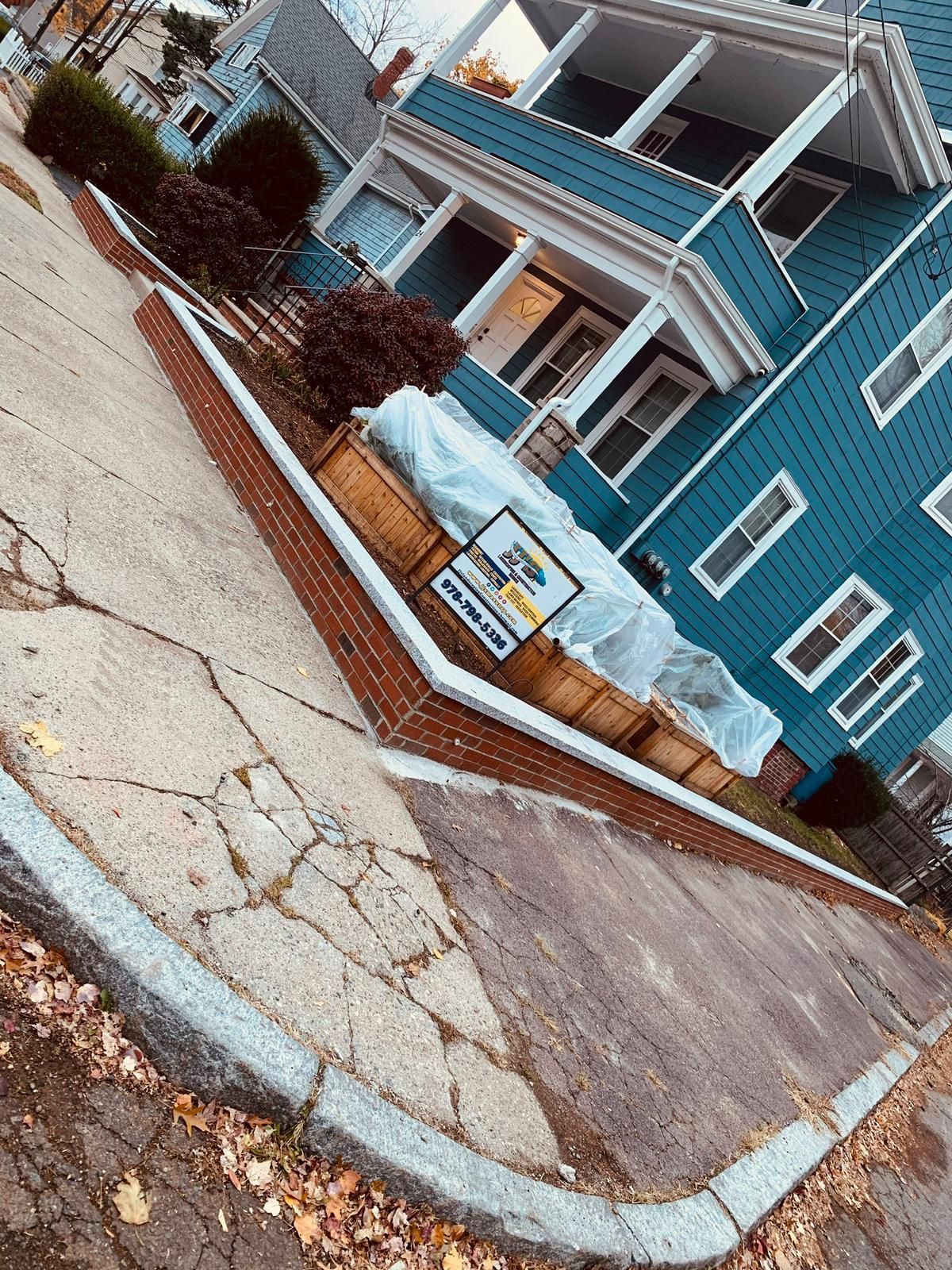A blue house with a sign on the sidewalk in front of it.