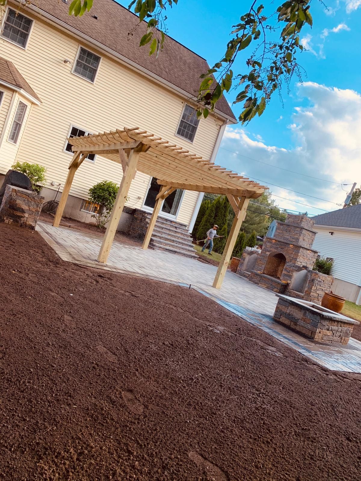 A wooden pergola is in the backyard of a house.
