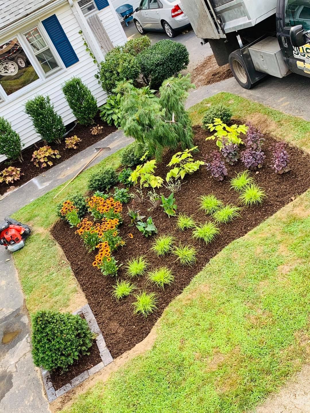 A lawn mower is sitting in a garden in front of a house.