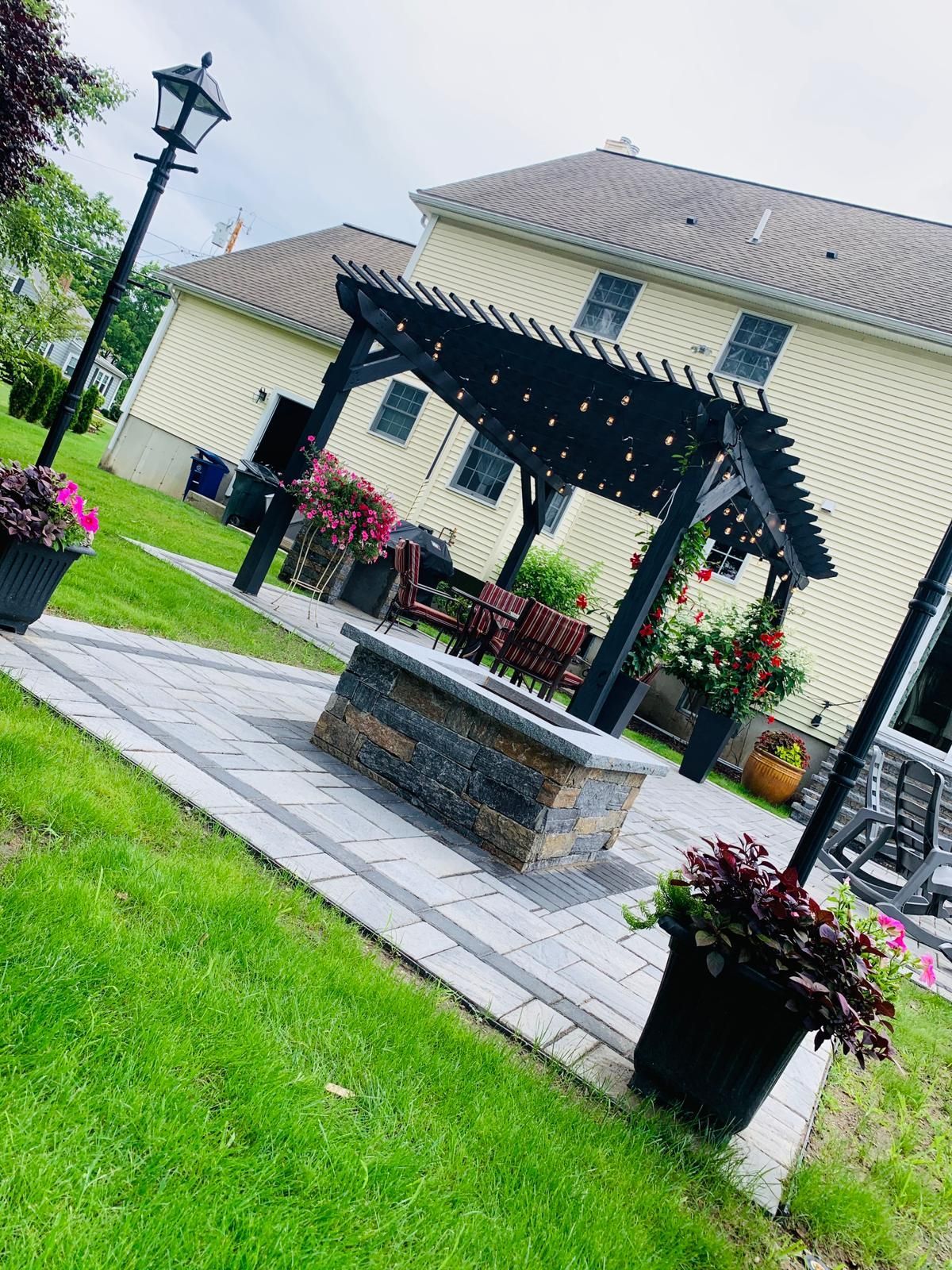 A large house with a pergola and a fire pit in front of it.