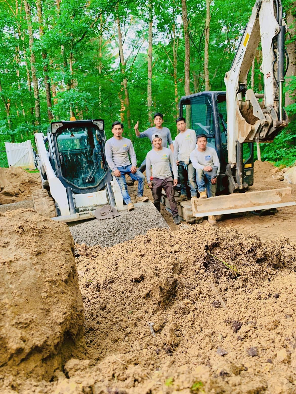 A group of men standing next to a bulldozer in a dirt field.