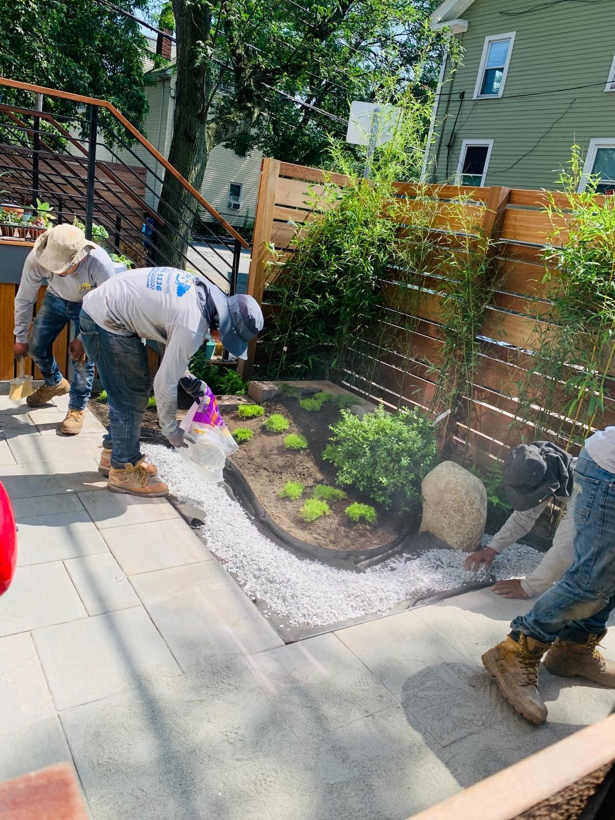 A group of men are working on a garden in a backyard.