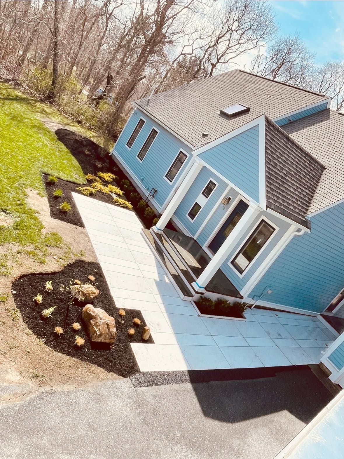 An aerial view of a blue house with a walkway leading to it.