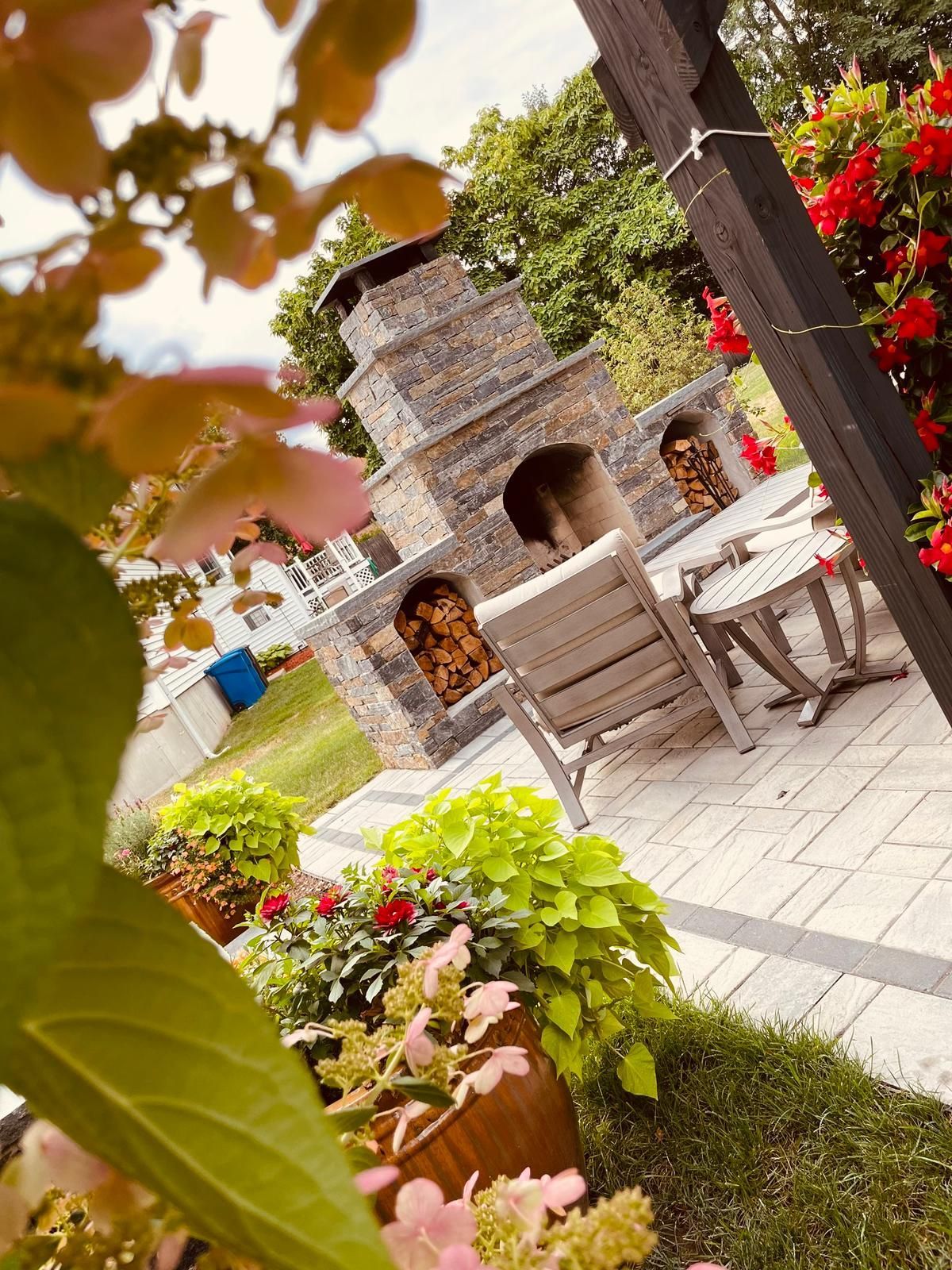 A patio with a fireplace, chairs, and flowers.