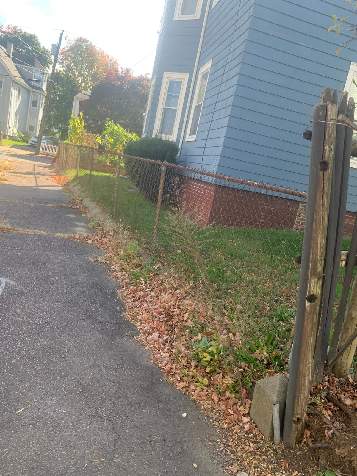 A chain link fence is along the side of a road next to a house.