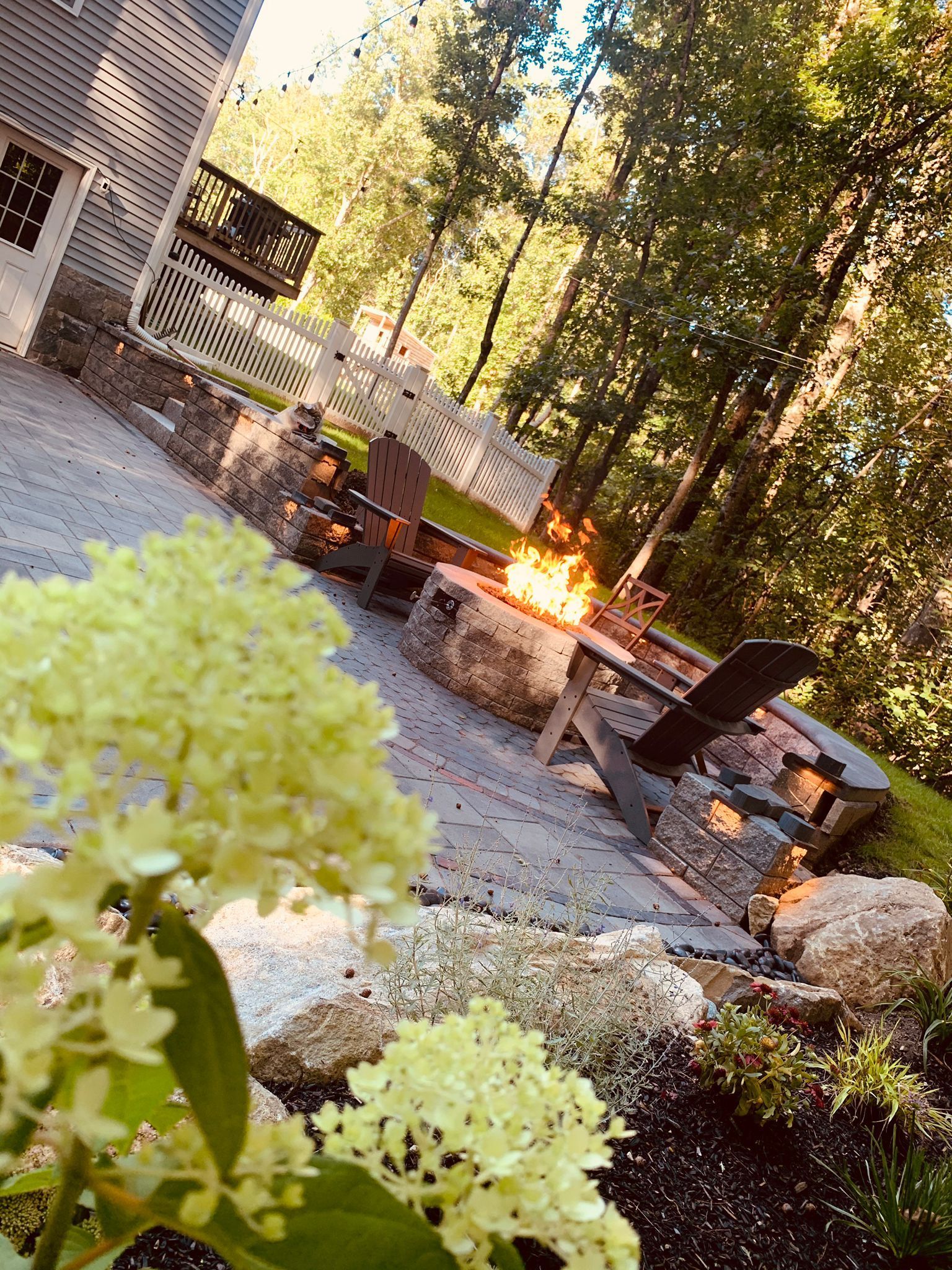 A patio with a fire pit and chairs in the woods.