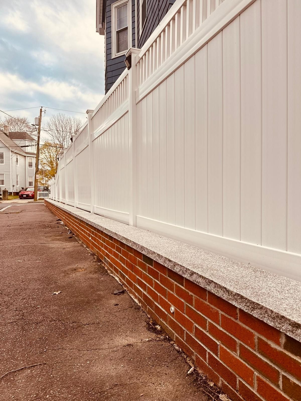 A white fence is sitting next to a brick wall.