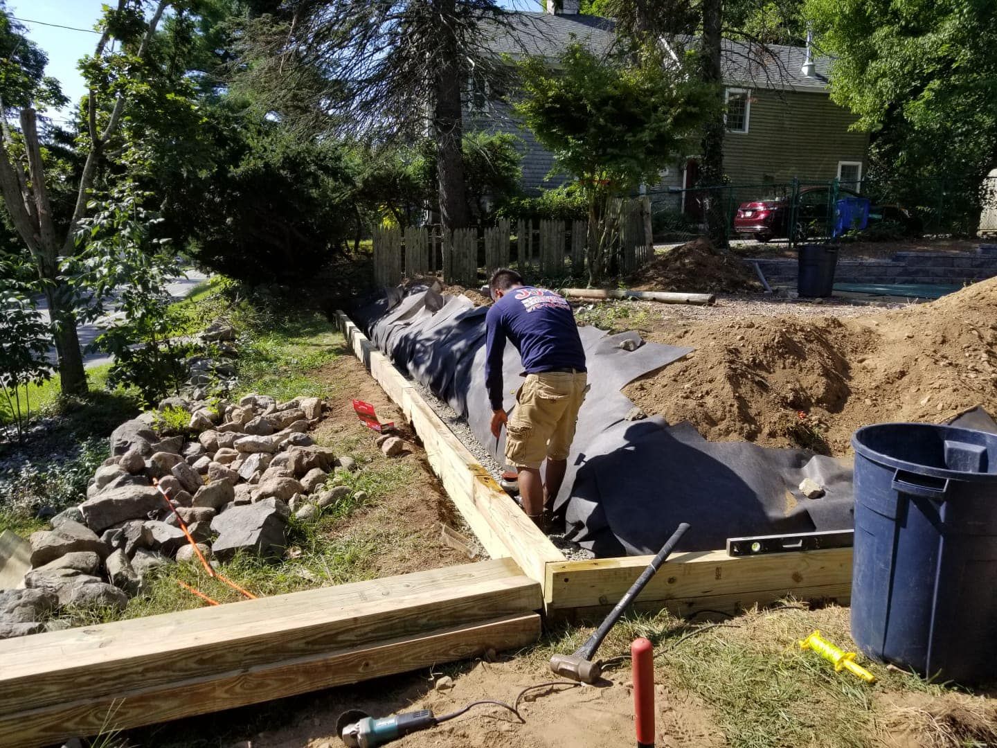 A man is working on a wooden fence in a yard.