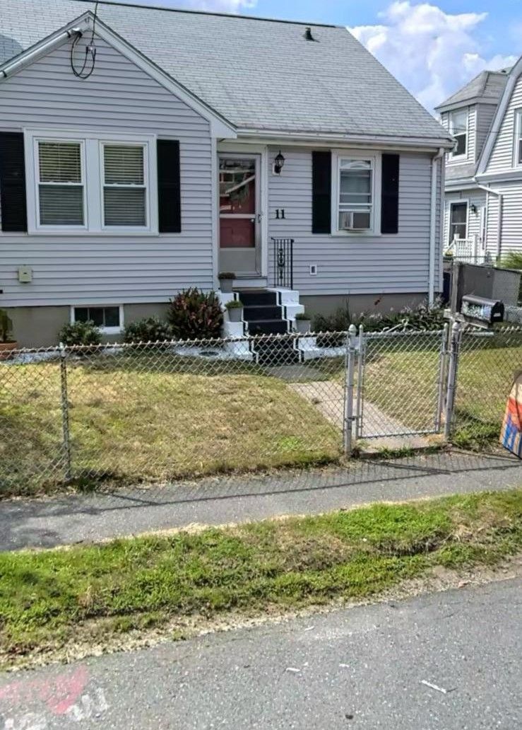 A white house with black shutters and a fence in front of it.