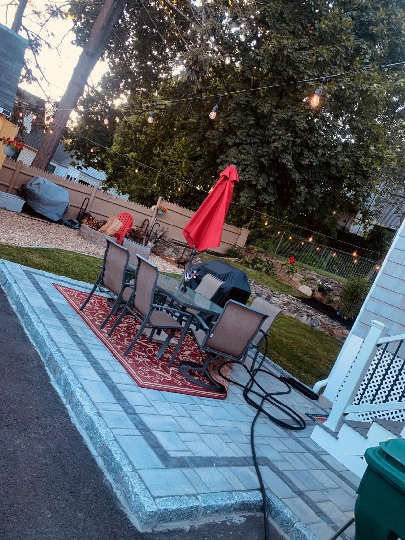 A patio with a table and chairs and a red umbrella.