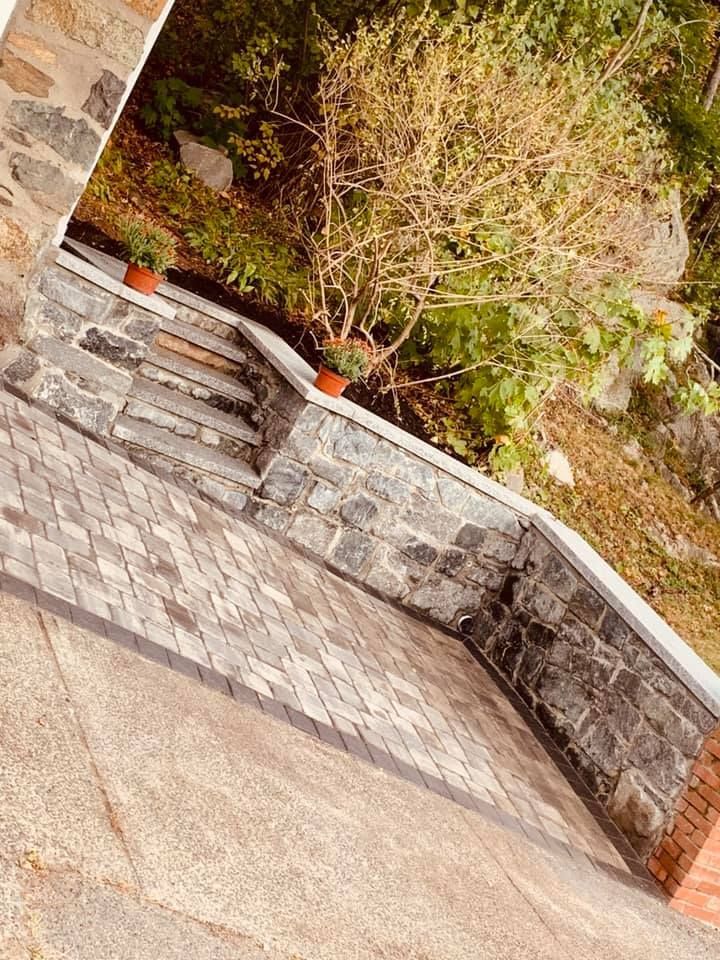 A stone wall with stairs and potted plants on it