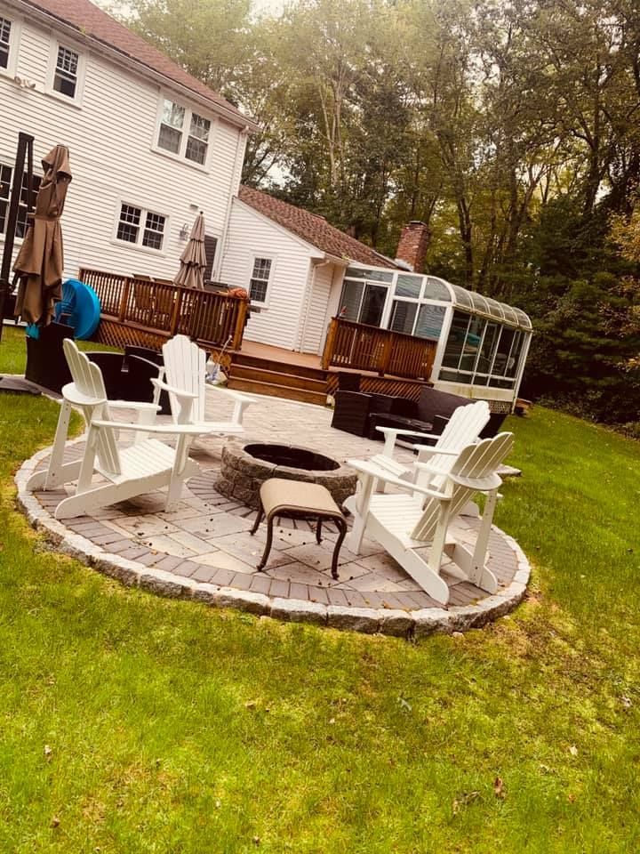 A patio with chairs and a fire pit in front of a house.