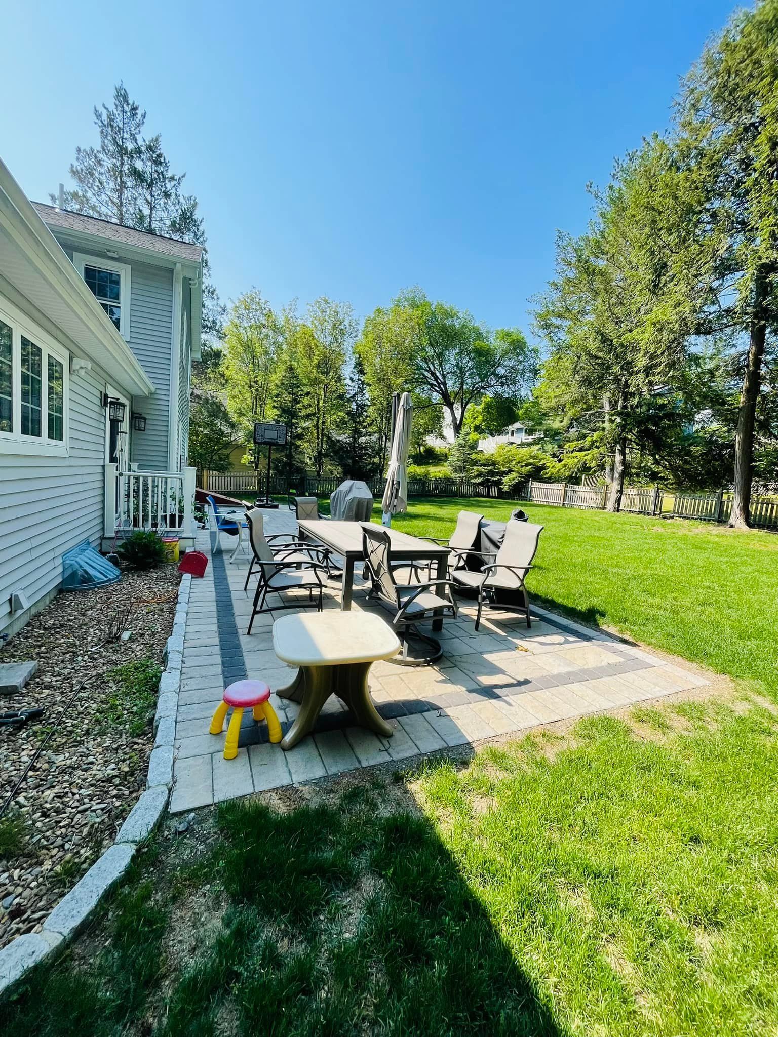 A backyard with a patio and a table and chairs in front of a house.