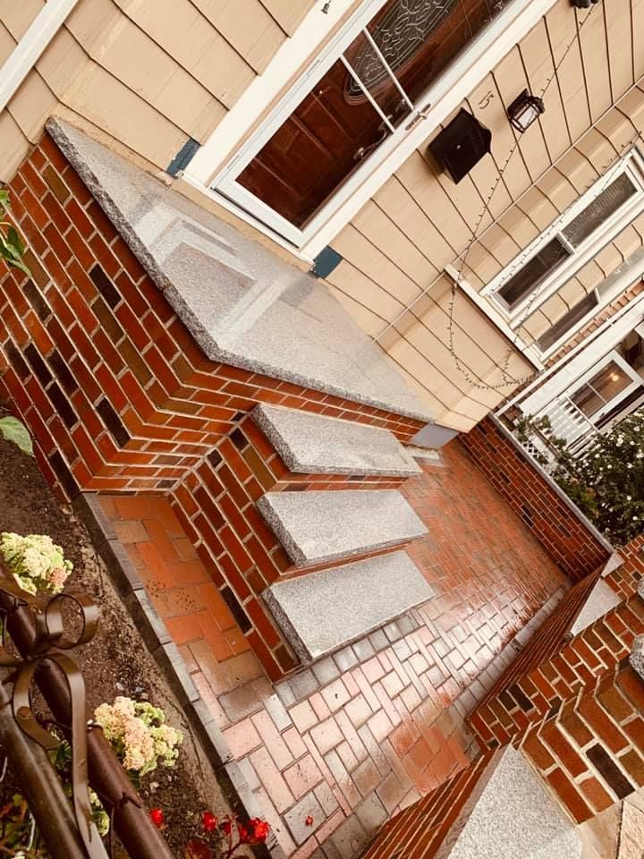 A brick porch with stairs leading up to the front door