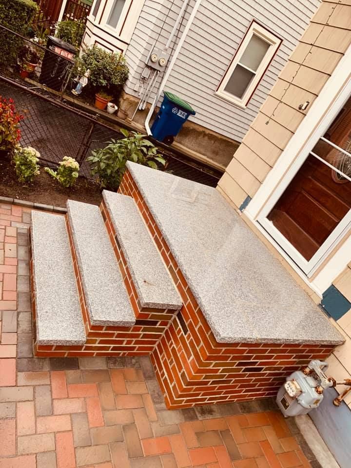 A brick porch with granite steps leading up to it