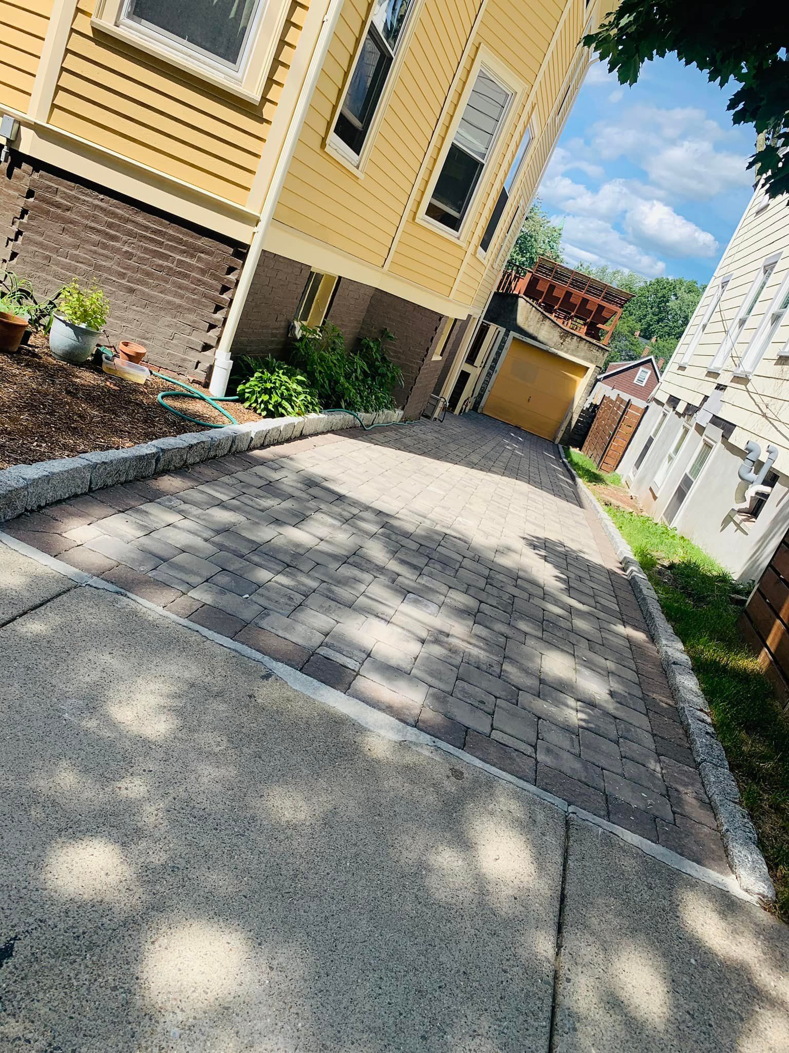 A brick walkway leading up to a yellow house.