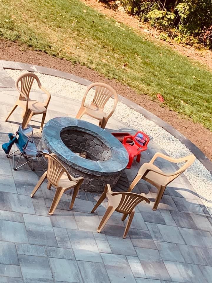 A fire pit with a table and chairs around it on a patio.